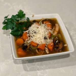 Rooster wild rice soup in a square white bowl topped with fresh parsley