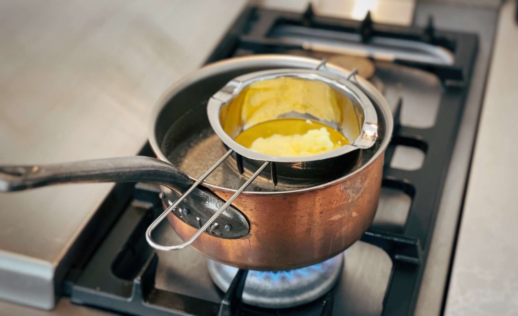 Melting tallow in a double boiler on a gas range.