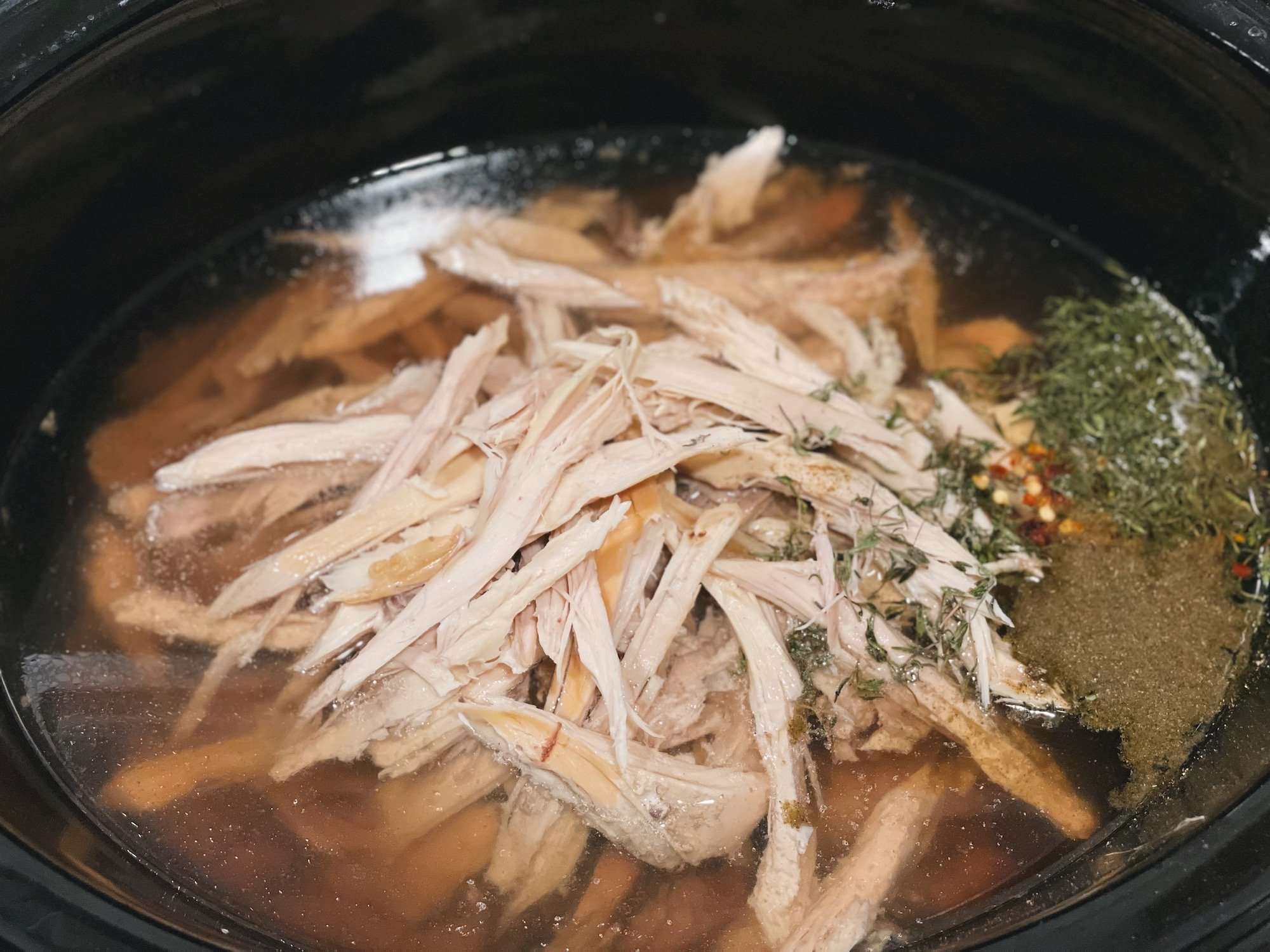 Shredded chicken in crockpot with herbs