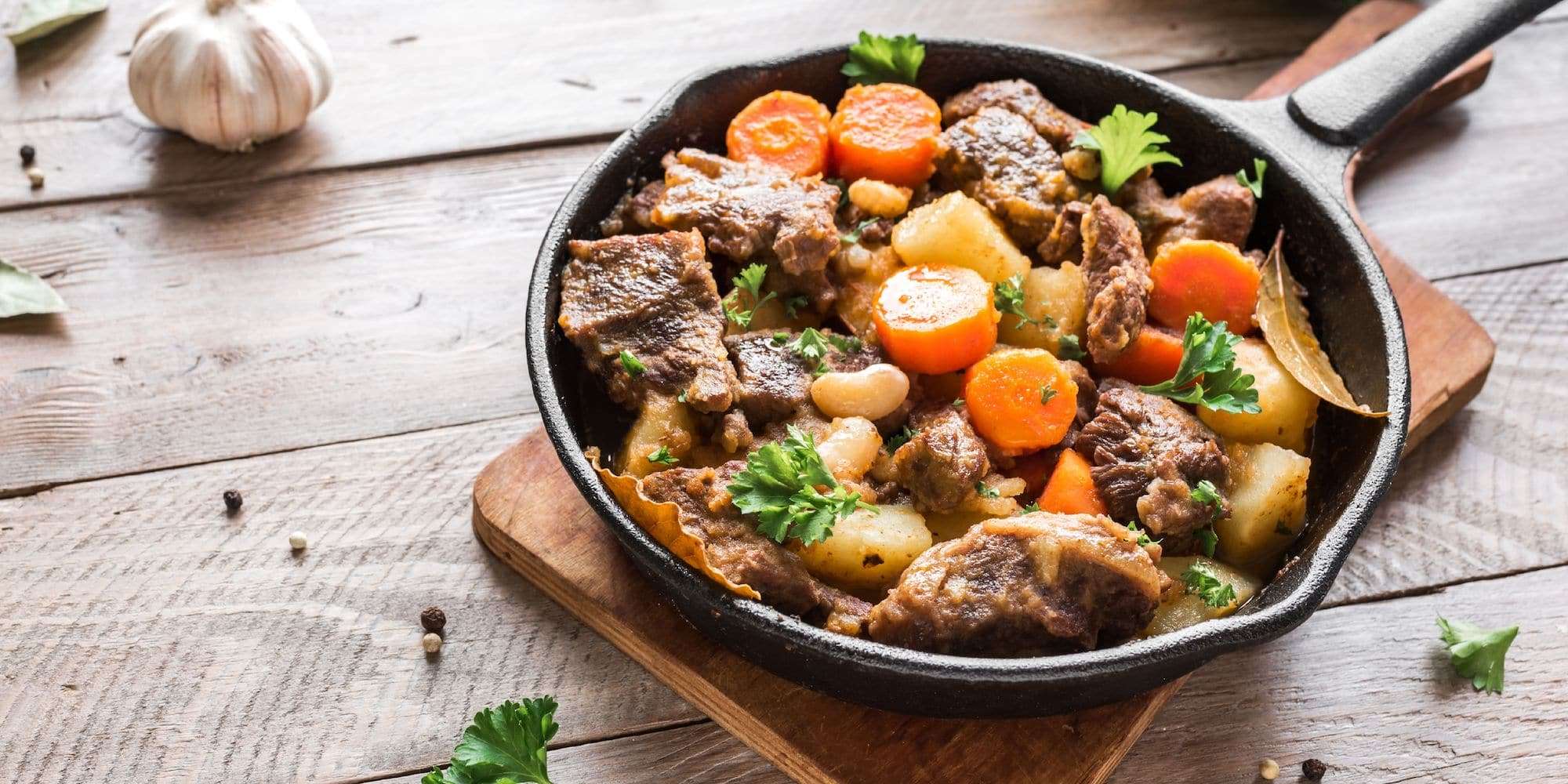 Beef, carrots, potatoes and beans in a cast iron skillet