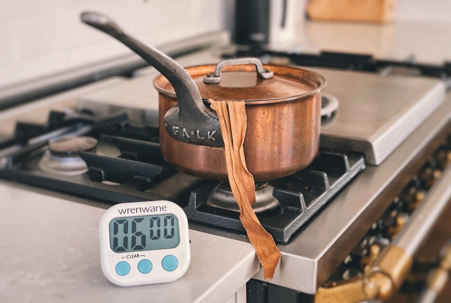 A copper pot brewing kombucha tea. A timer set to 6 minutes sitting in front of it.