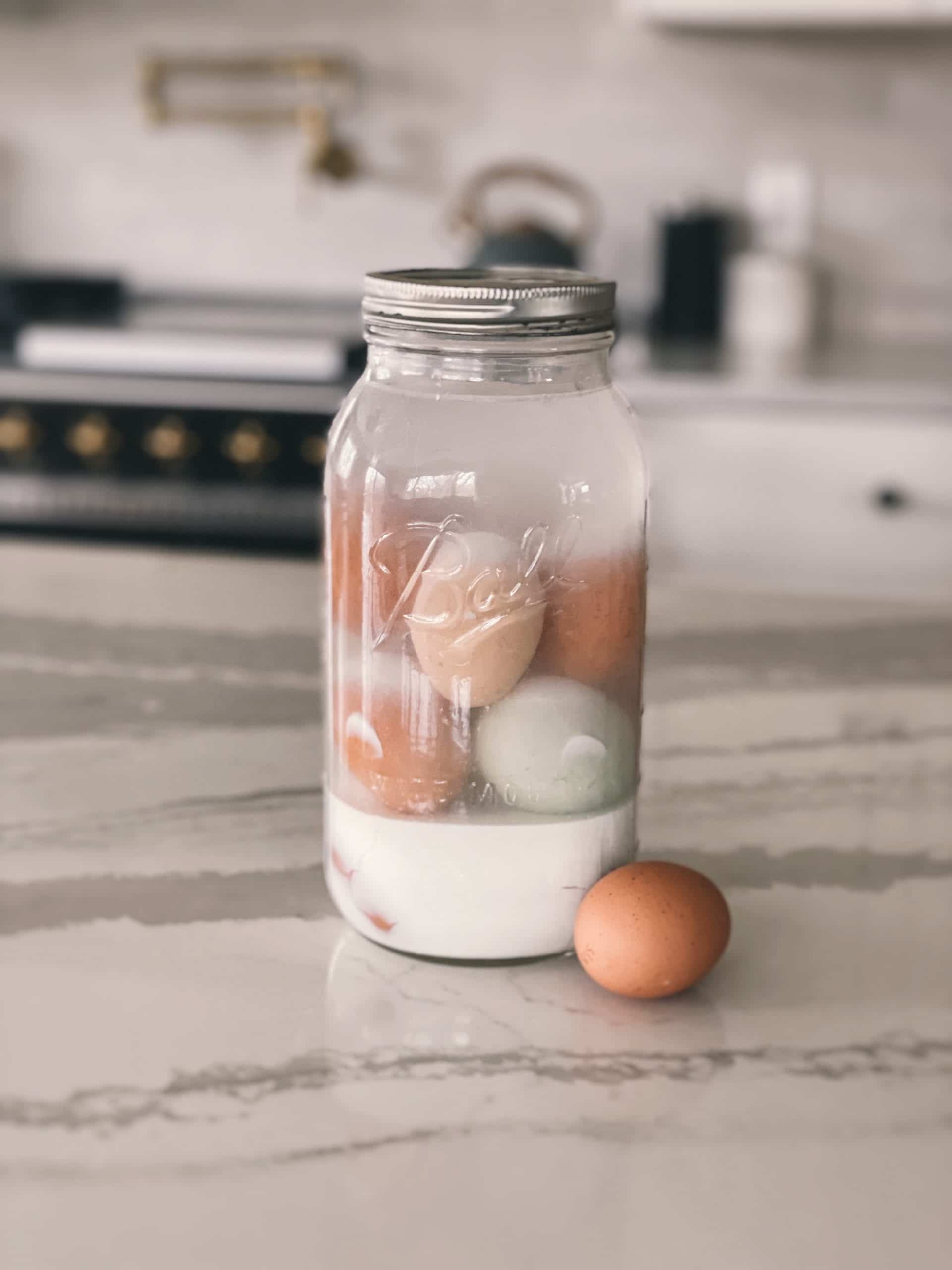 A half gallon glass mason jar filled with eggs and a lime mixture