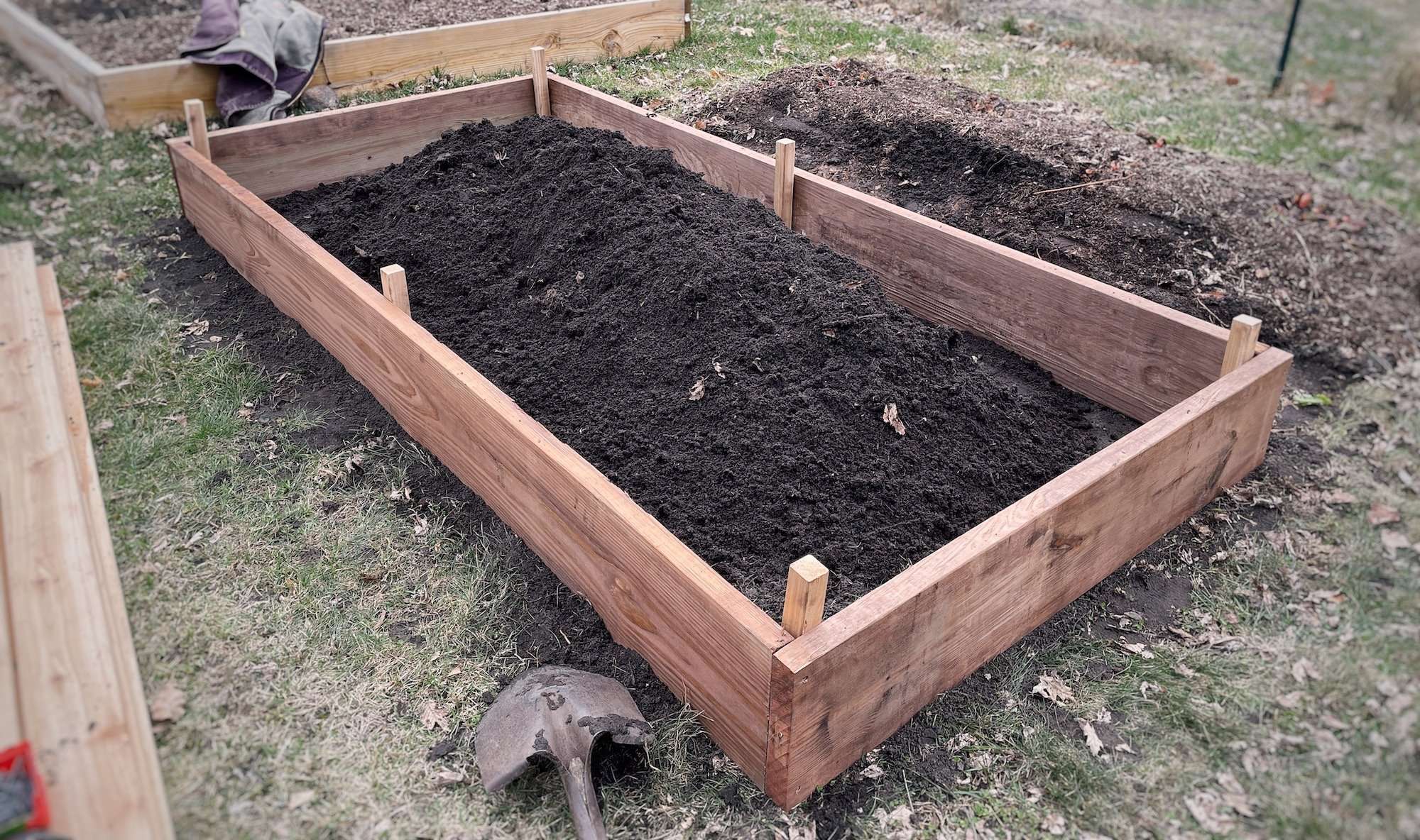 Driving in cedar stakes to secure the raised garden bed