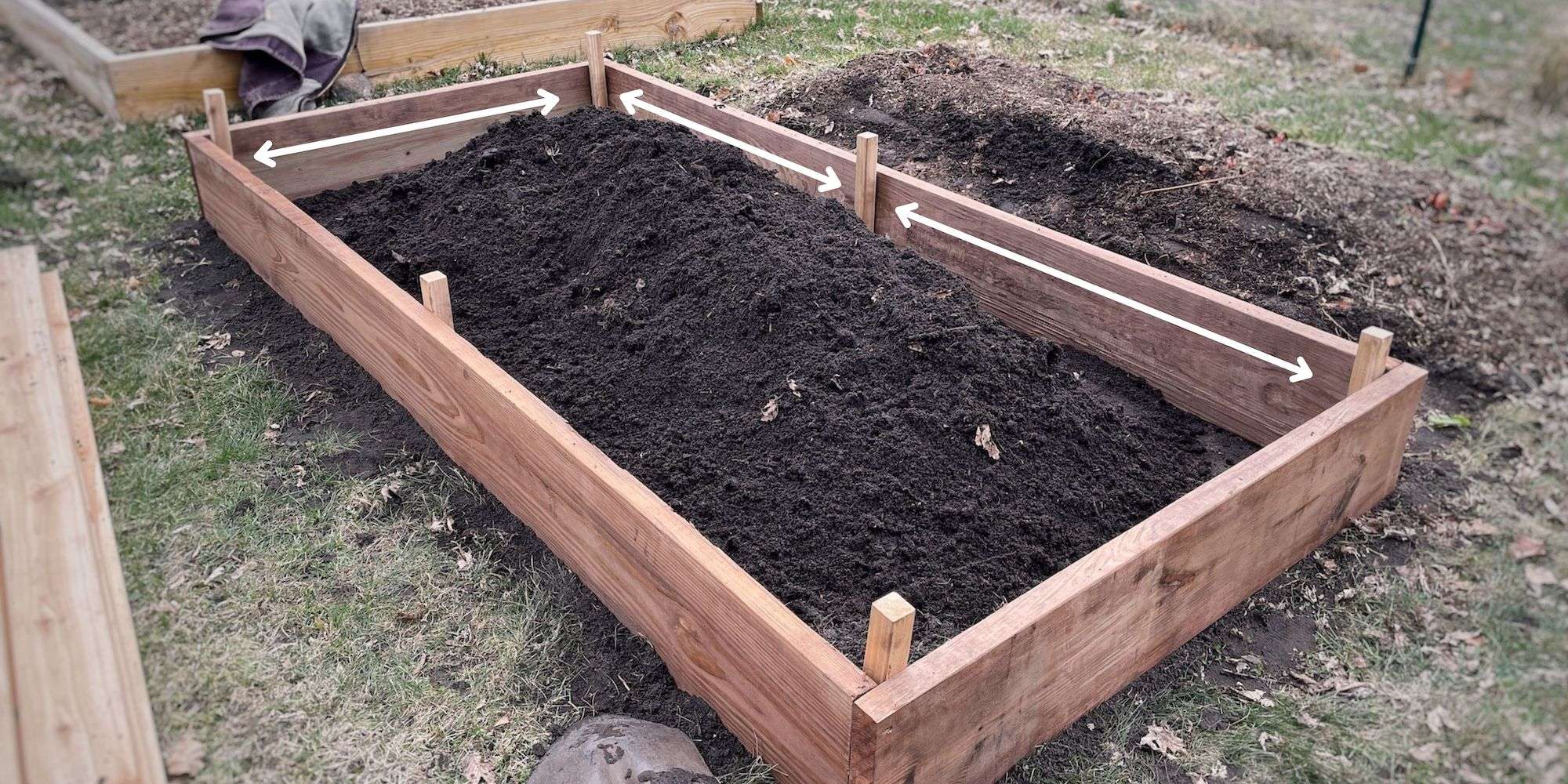 Arrows drawn on raised bed to show which area to measure to fit the cedar decking