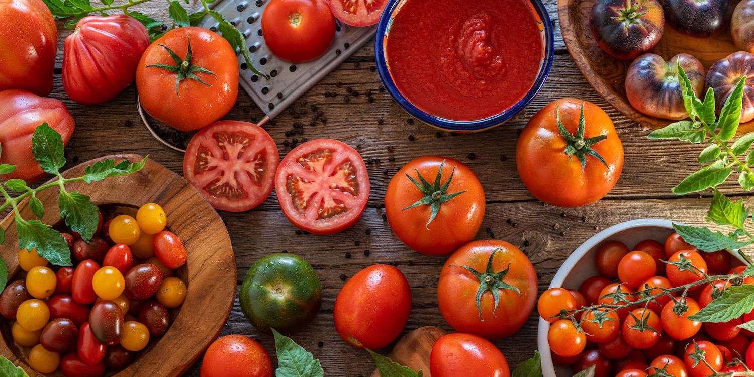 Many types of tomatoes spread out over a wooden table