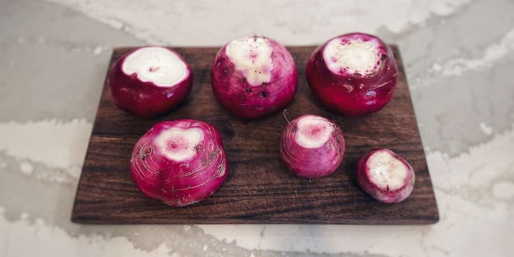 Trimmed pink radishes placed on a wooden cutting board