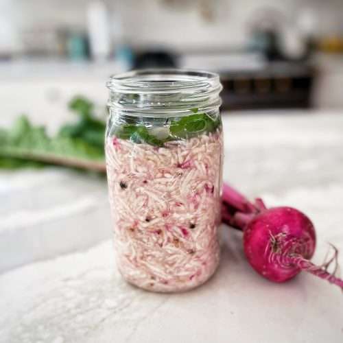 Fermented Turnips or Sauerruben freshly made in a jar on the counter with a turnip next to it.