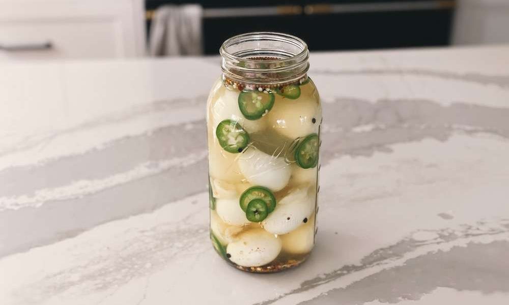 A half gallon mason jar filled with finished jalapeno pickled eggs to cool