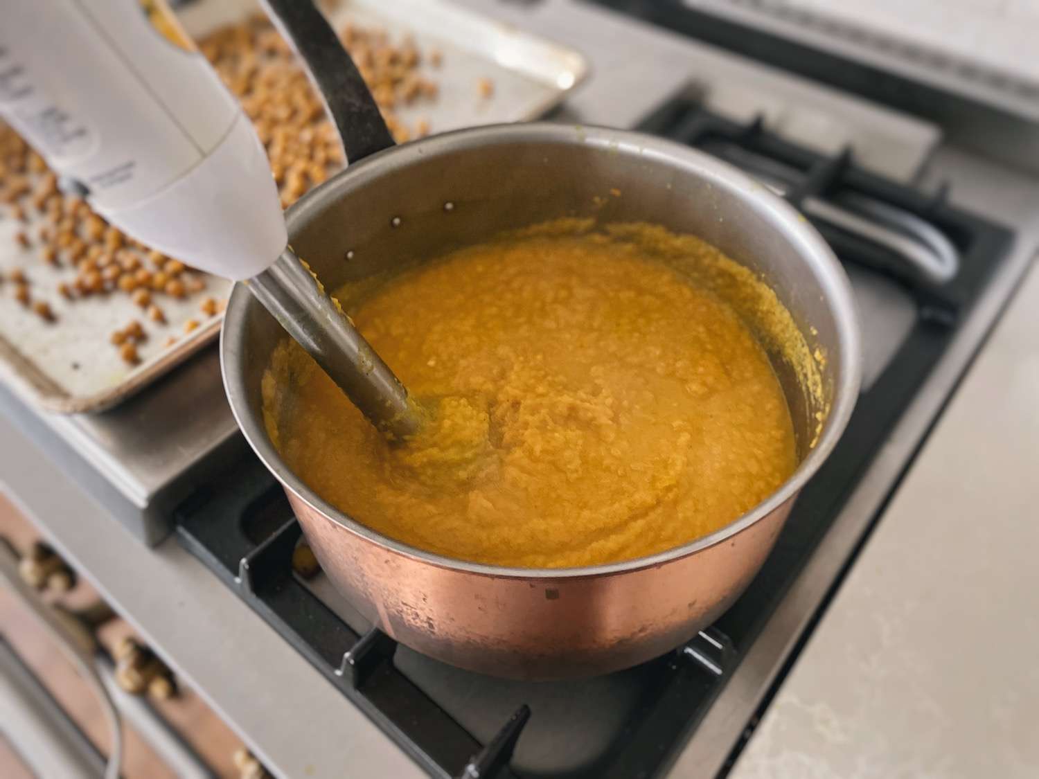 Swede soup being blended with an immersion blender while in a large soup pot