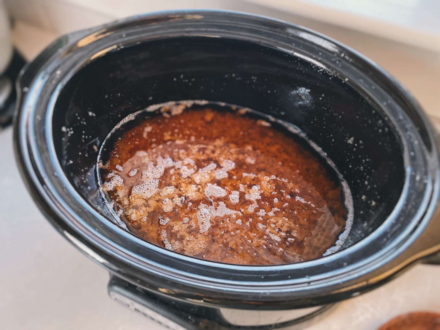 A crockpot filled with golden rendered down tallow with cracklings