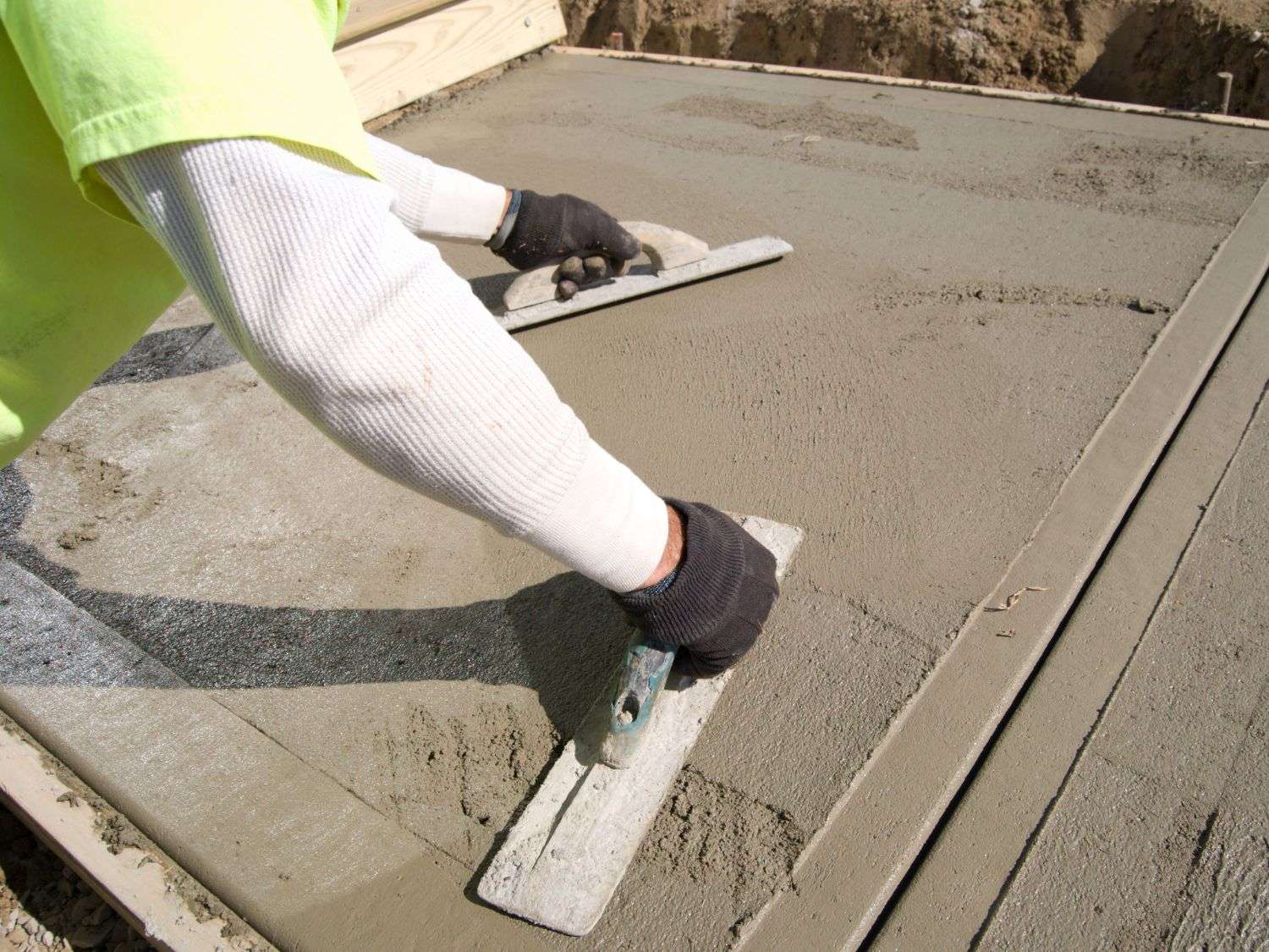 A photo of two people tamping down fresh concrete