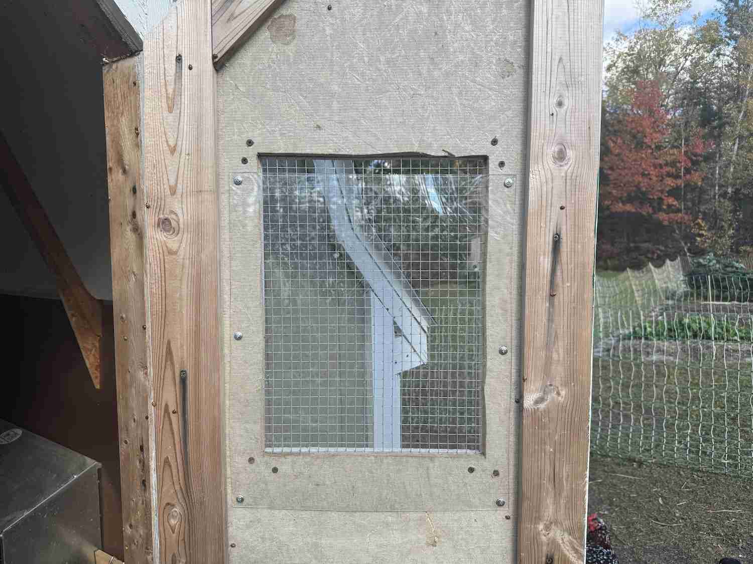 A photo showing a sheet of polycarbonate partially covering a window in the chicken coop
