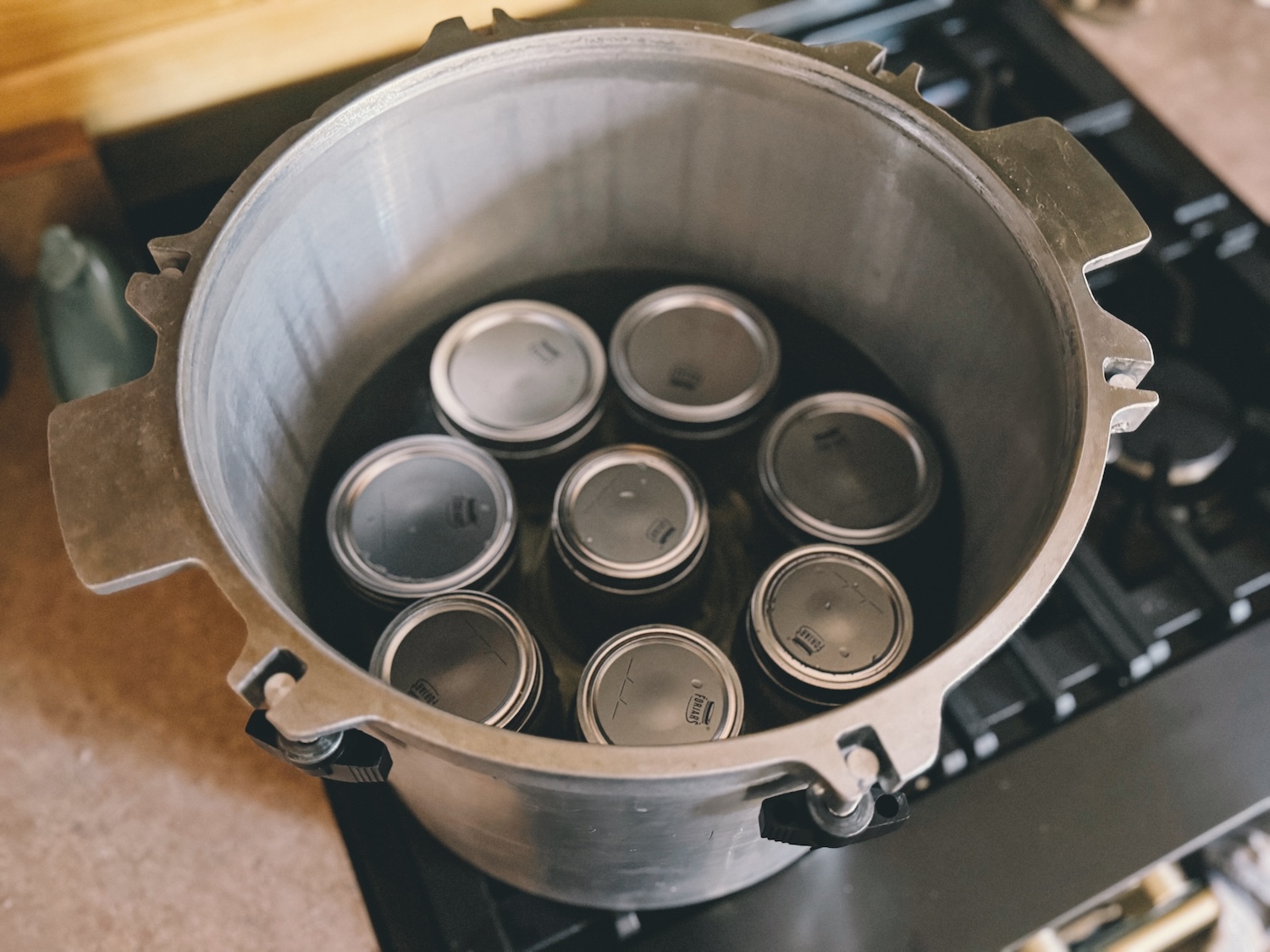 A photo showing a pressure canner loaded up with 8 jars on the bottom