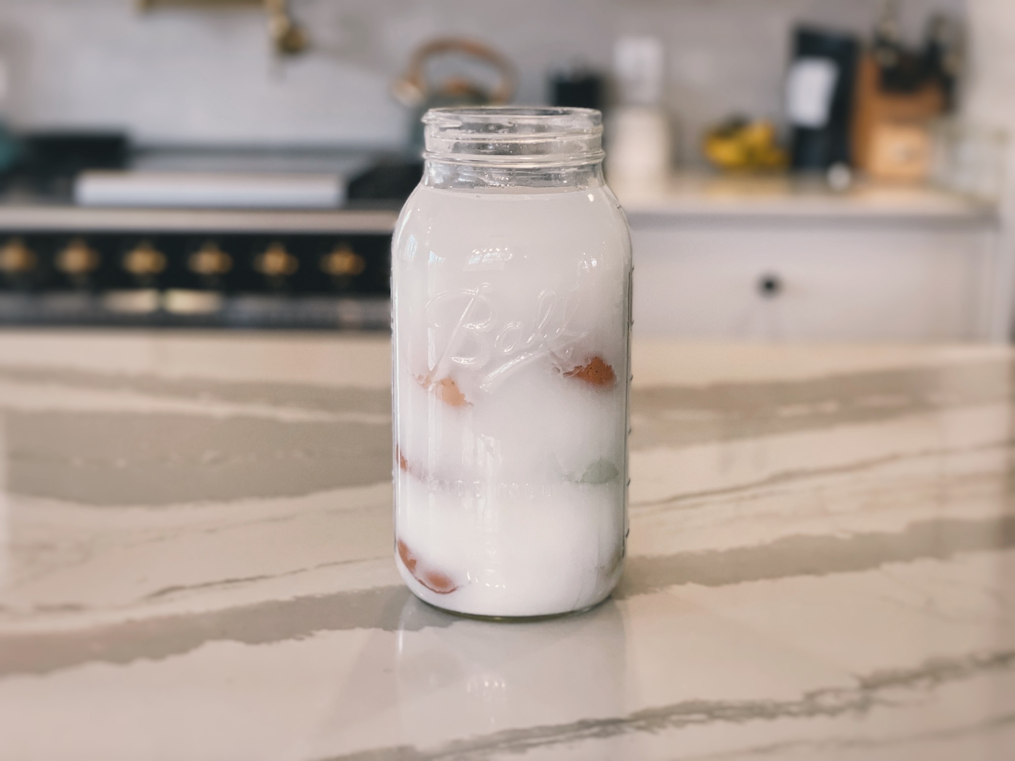 Freshly water glassed eggs in a half gallon glass mason jar on a kitchen island