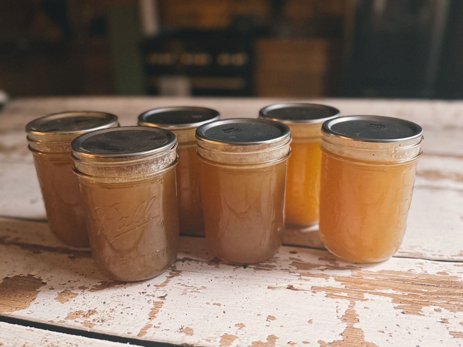 6 jars of pressure canned bone broth sitting on a wooden kitchen island