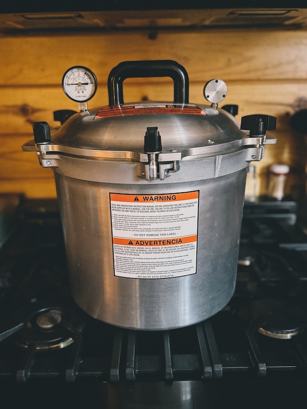 A photo showing an All-American canner on a range with a wooden background