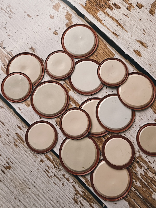 Many used canning lids laid out on a weathered wooden background