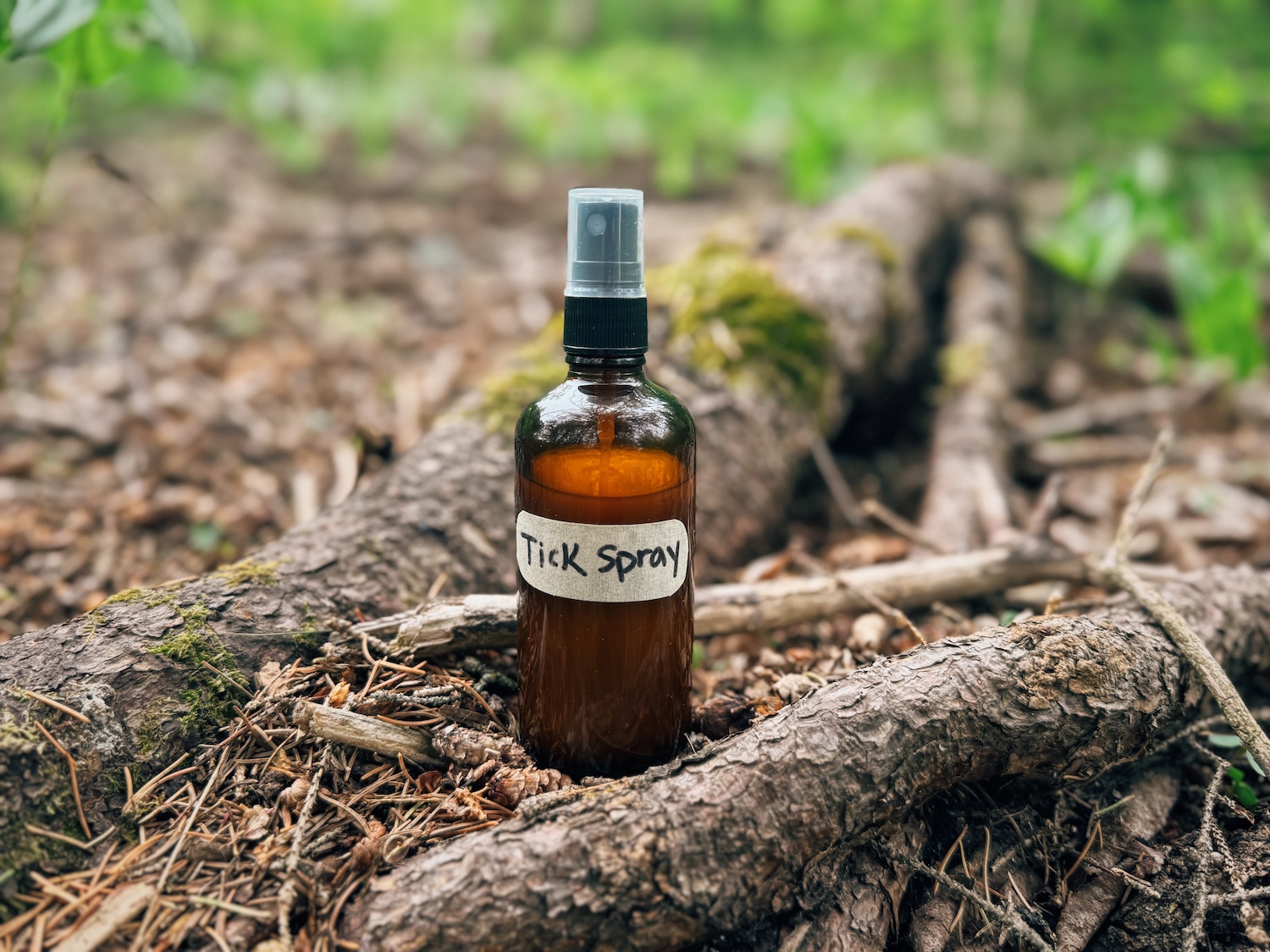 A bottle of DIY tick repellent sitting on the floor of the woods