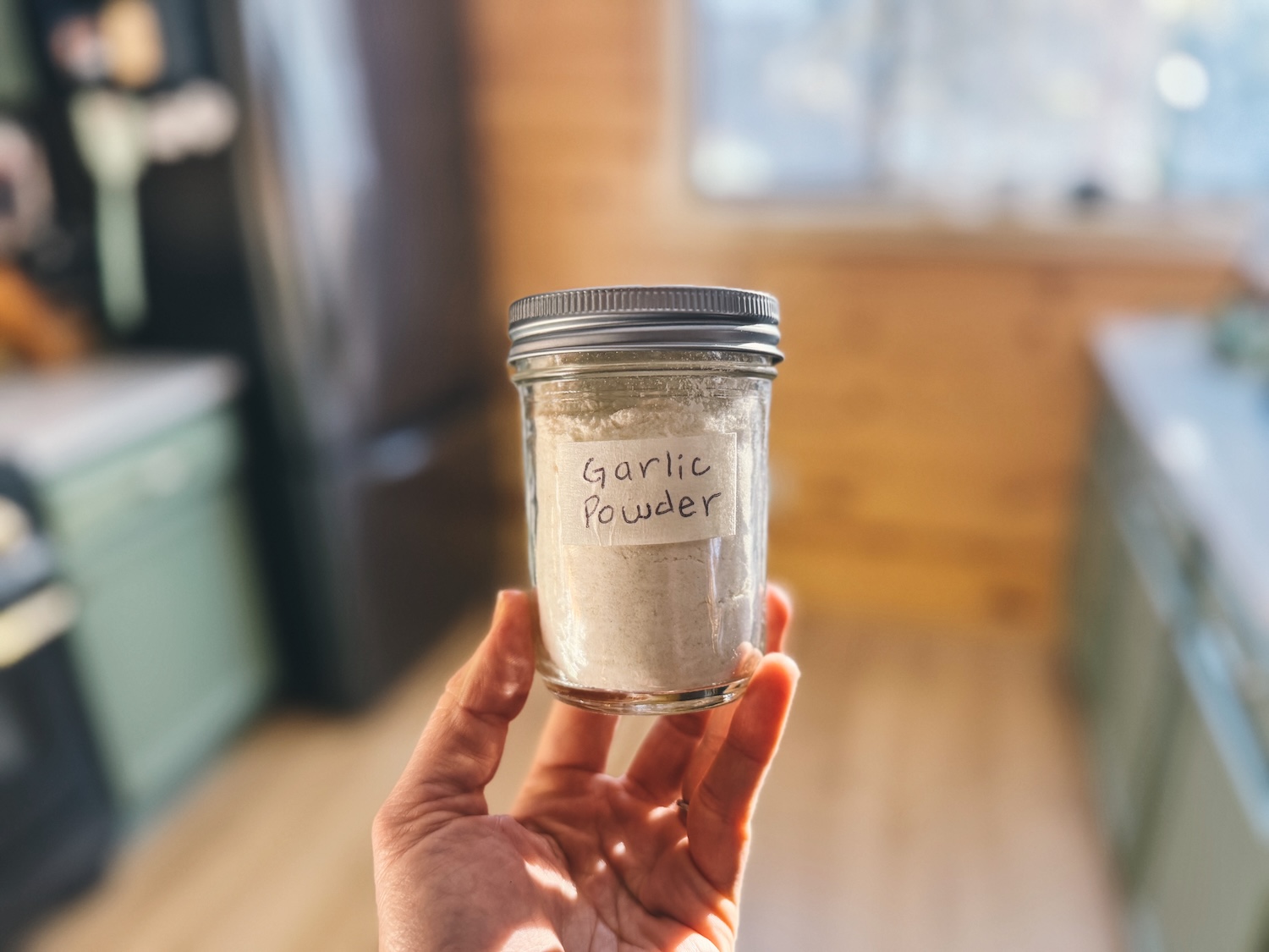 Holding up a mason jar filled with homemade garlic powder in a kitchen