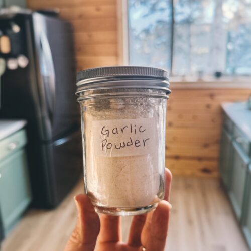 Holding up a mason jar filled with homemade garlic powder in a kitchen
