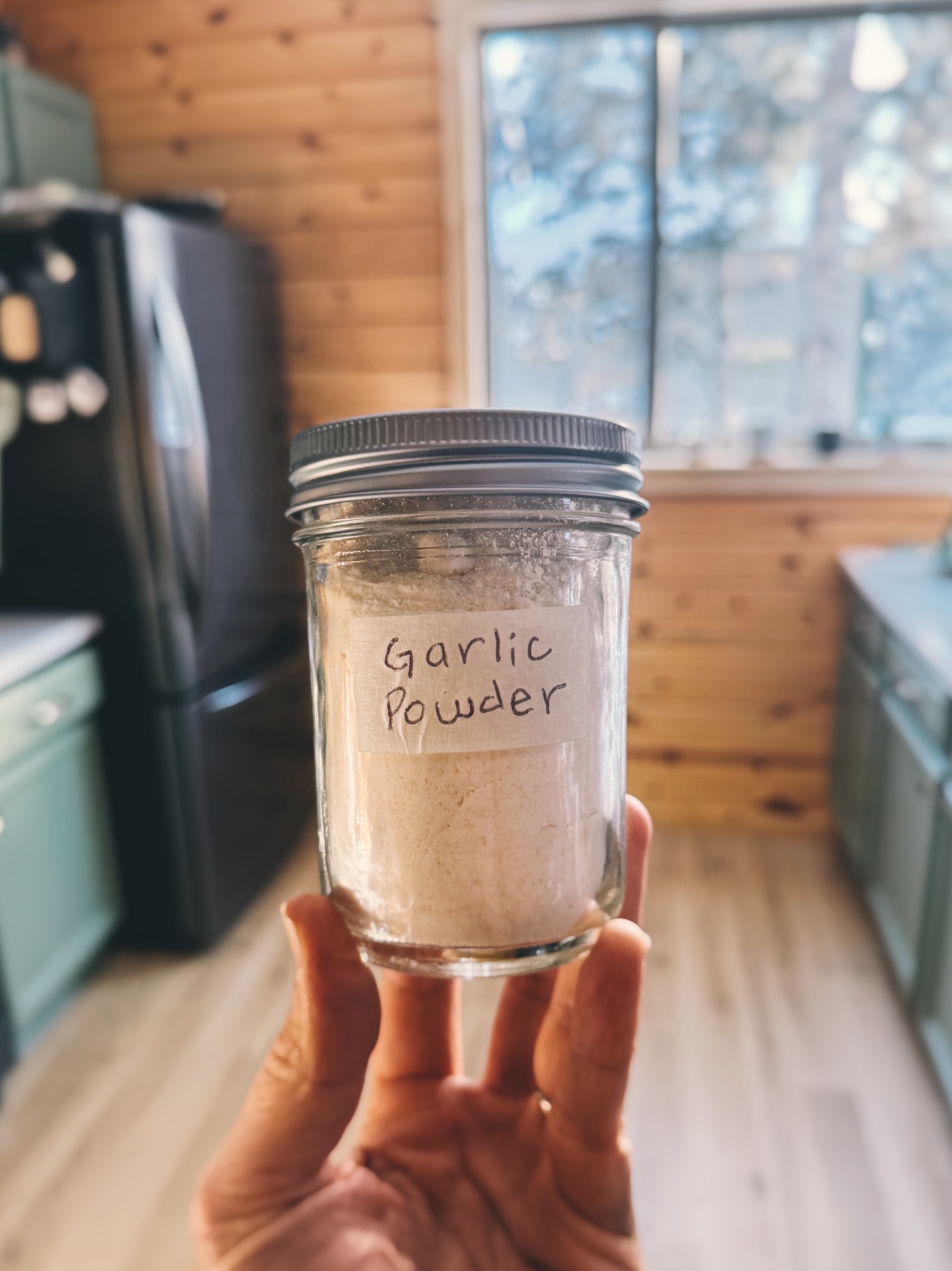 Holding up a mason jar filled with homemade garlic powder in a kitchen