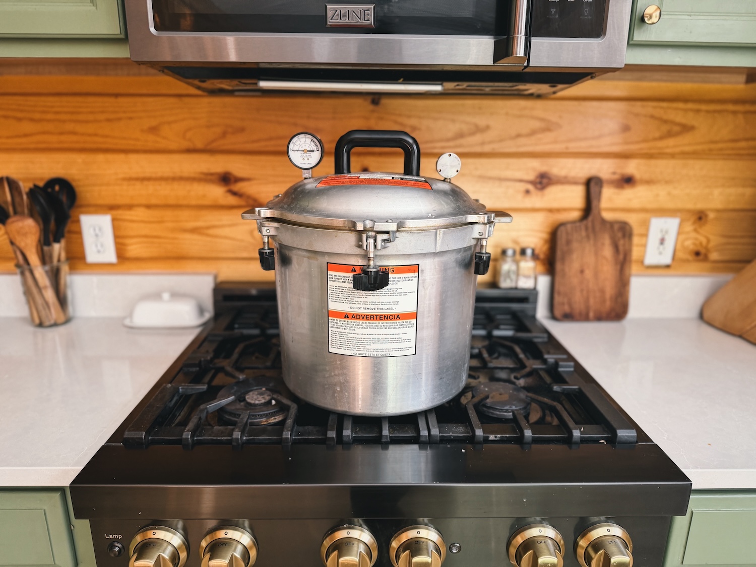 A photo of an All American Pressure Canner sitting on range with the lid and weight on