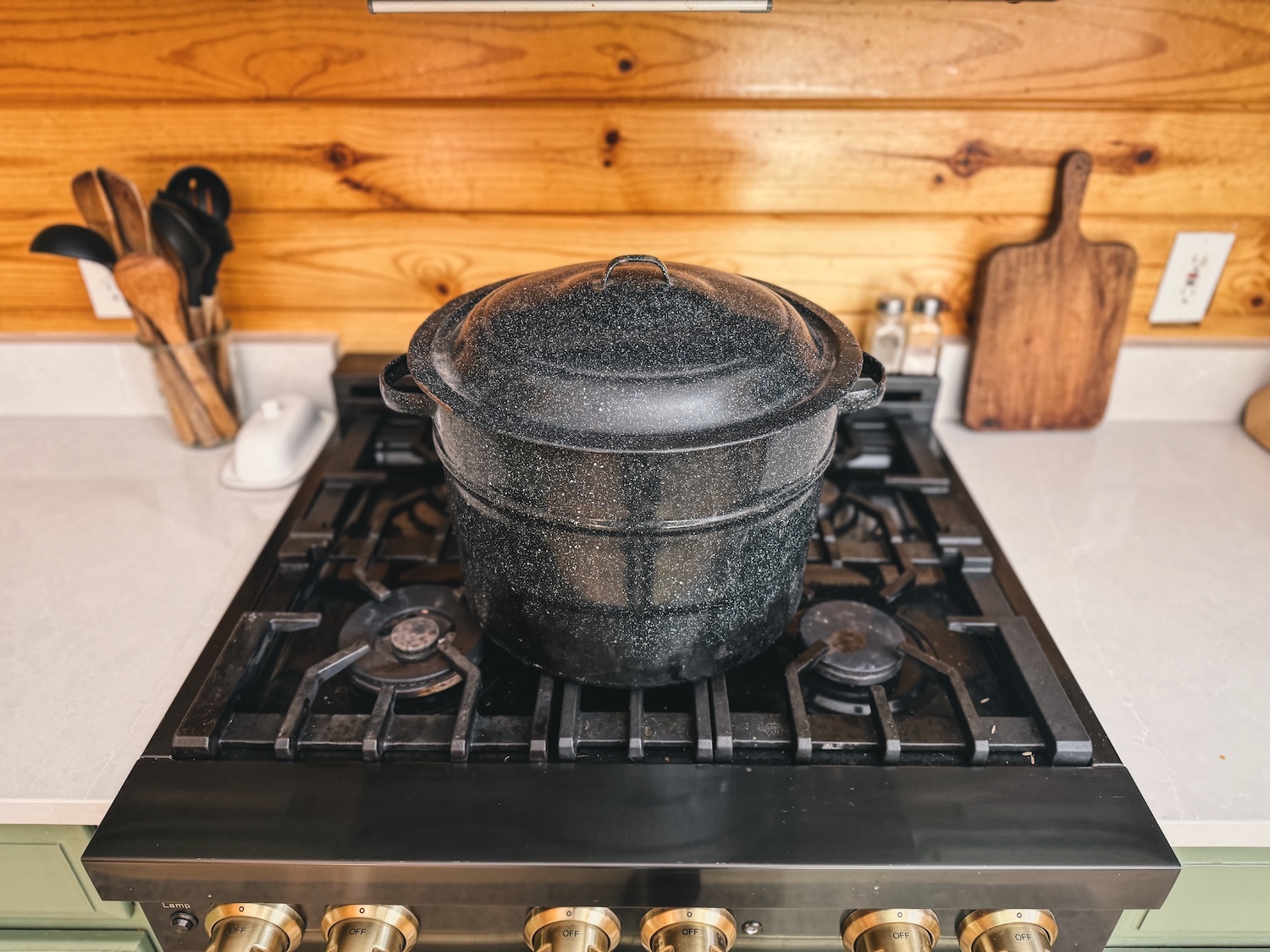 A photo of a water bath canner sitting on a kitchen range with the lid on